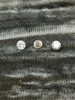 Top view of three round cut loose diamonds placed side by side on fabric showing size and sparkle.