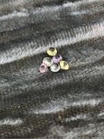 Six loose sapphire gemstones in multiple pastel colors on a grey textured background
