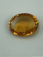 Close-up image of the oval faceted citrine gemstone showing its yellow-orange color and facet cuts.