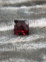 Top view showing the deep red color and faceted cut of the square Mozambique garnet gemstone.