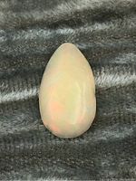 Teardrop-shaped opal cabochon showing smooth polished surface and soft play-of-color.