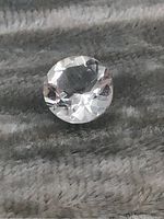 Close-up photo of a round faceted prasiolite gemstone showing clarity and facets.