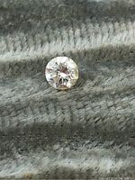 Photo showing the top view of the small round brilliant diamond on textured fabric background.