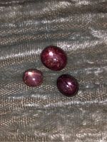 Three star rubies placed on fabric showcasing size and star effects under light.
