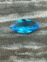 Marquise cut blue topaz gemstone showing top-down view of the stone with bright blue tone and light reflection.