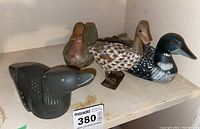 Shelf with carved soapstone loon in front and three wooden duck decoys behind it