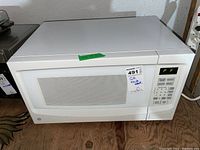 Front view of white GE microwave showing window and control panel with digital display reading 'PF'.