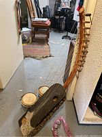 Adungu 11-string African harp with two bongo drums and pink tambourine on basement floor.