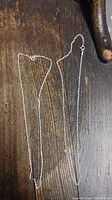 Two sterling silver chains laid flat on wood surface, marked with stamp 925.