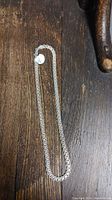 Sterling silver necklace laid flat on a dark wooden surface with a visible tag indicating it is stamped 925 Italy.