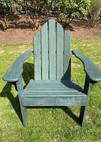 Front view of weathered dark green wooden Adirondack chair with wide armrests