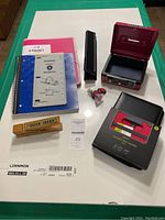 Top view of all items on white IKEA Linnmon desktop, showing notebook, folder, safe, magnets, foldable box, stapler, and packaging label of Linnmon desktop.