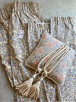 Bluebell floral pattern long and short lined drapes, square cushion with white piping, and twisted rope swags with tassels laid out on carpet.