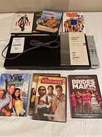 Top view of Sony DVD player with remote, manual and six comedy DVD cases.