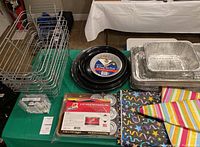 Top-down view of chafing trays, prep plates, gel heaters, napkins, and LED tea lights spread on a green tablecloth.