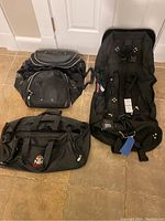 Photo showing all three items: one golf club glove carrier and two black duffel bags placed on tiled floor, highlighting overall condition and design features