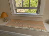 Laura Ashley throw blanket laid flat showing beige color, soft texture, fringed edges, and green accent stripes.