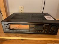 Front view of ONKYO TX-903 amplifier showing power and function buttons, headphone jack, and the amber digital tuner display.