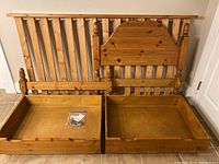 Full view of twin bed components including two drawers, slatted base, and headboard.