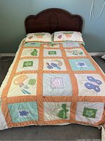 Full view of double bed made with patchwork quilt featuring floral and butterfly patterns and two matching pillows.