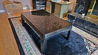 Full view of black lacquer coffee table with white specks and rounded corners.