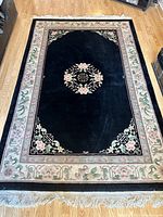 Top-down view of the decorative carpet showing overall design, central motifs, border patterns, and fringe detailing.