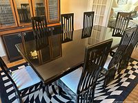 Full view of black lacquer dining table and eight chairs arranged in room