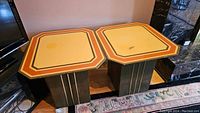 Pair of retro-style end tables with solid base and decorative tops placed side by side, showing color, design, and condition.