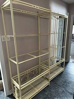 Two empty shelving units with metal frames and wooden shelves placed side by side against a wall.
