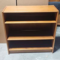 Front view of wooden three-shelf bookshelf showing three shelves and smooth wood finish.