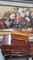 Two wooden boxes on a table in front of a floral painting, showing overall size and appearance.