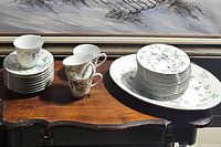 Full view of cups, saucers, salad plates stacked and oval platter on wooden table, showing overall quantity and condition.