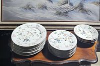 Photo of dinner plates, salad plates, and bowls with floral pattern on a wooden table.