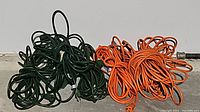 Coiled green and orange extension cords on a concrete floor
