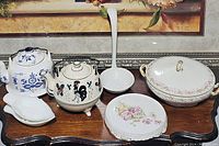 All eight pieces arranged together on a wooden surface showing various items in the set including teapot, sugar bowl, ladle, plates, and casserole dish.