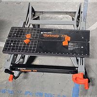 Top view of Black & Decker Workmate 225 portable project center with orange vises on black metal grid-marked surface and folding gray legs.