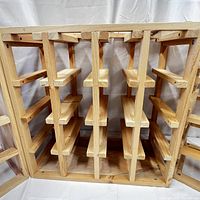 Close-up photo showing interior slatted wooden compartments for holding individual wine bottles horizontally in a cube-shaped wine rack.