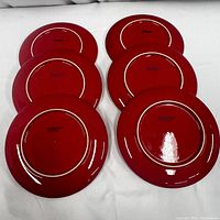 Set of six red plates displayed upside down showing the bottoms with Crate & Barrel markings.