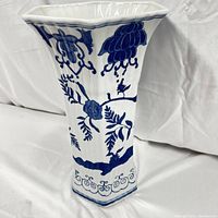 Side view of the octagonal white ceramic vase adorned with blue floral and bird patterns, showing the flared top rim and detailed scrollwork at base
