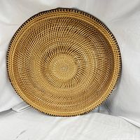 Top-down image showing the concentric handwoven rattan pattern in natural brown tones on the oval tray.