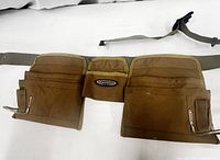 Full view of the brown canvas contractor's apron with multiple pockets and attached adjustable belt laid flat.