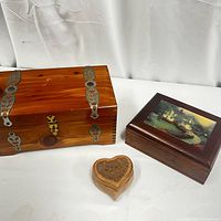 Closed view of the cedar chest, wooden jewelry box with scenic front panel, and heart-shaped jewelry box.