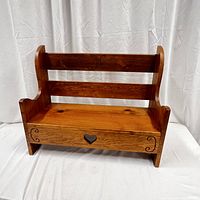 Front view of vintage wooden bench/plant stand showing hand carved heart and decorative side carvings.