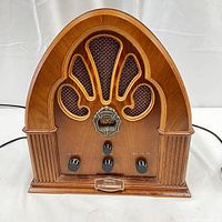 Full frontal view of vintage cathedral-style wooden radio with arched top and fabric speaker grille insert showing overall condition and design.