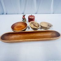 Photo showing entire wood serving set including long tray, three bowls, rabbit figure, and red lidded container against white background.