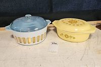 Two vintage Pyrex casseroles side by side: Blue Delphite on left, Kimchee on right.