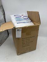 Open cardboard box with six packs of mattress bags visible inside, white plastic packs with product label shown