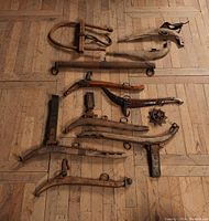 Wide shot showing various sizes and styles of wooden yoke trees with iron fittings laid out on wooden floor.