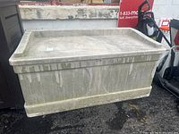 Photo of exterior side view of beige plastic deck box with some dirt and weathering