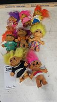 Eight vintage troll dolls arranged on a white surface showcasing various hair colors and outfits for clear identification.